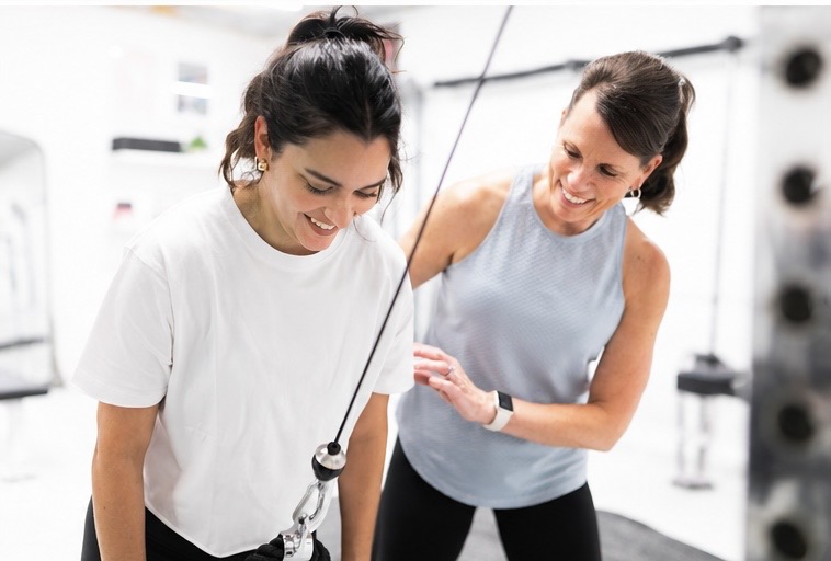 Cherie coaching a client on a cable exercise